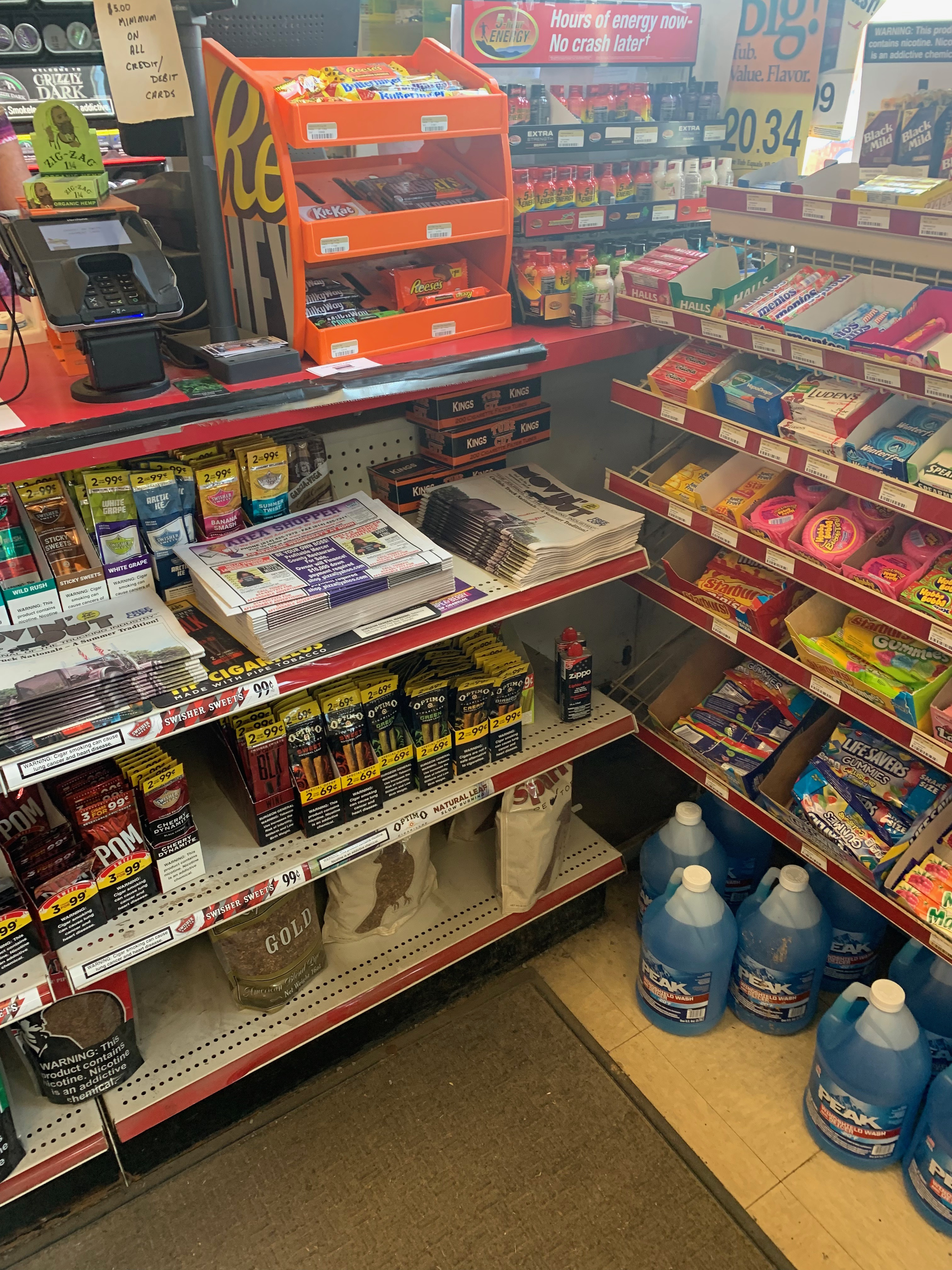 cigarillos on shelves accessible without clerk assitance, less than 3ft from the ground, and next to candy