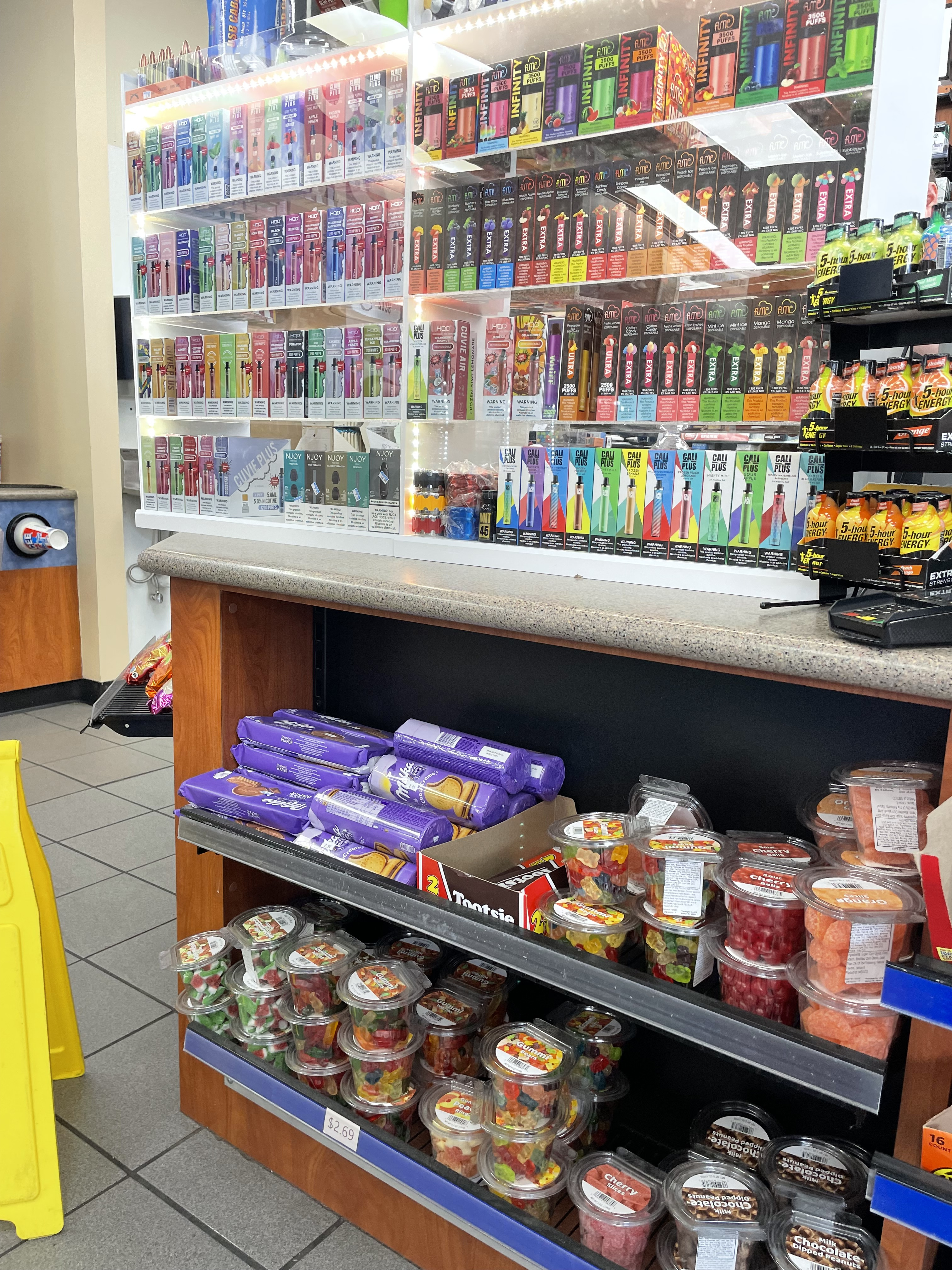 display of flavored e-cigarettes on the counter above gummies and sweets