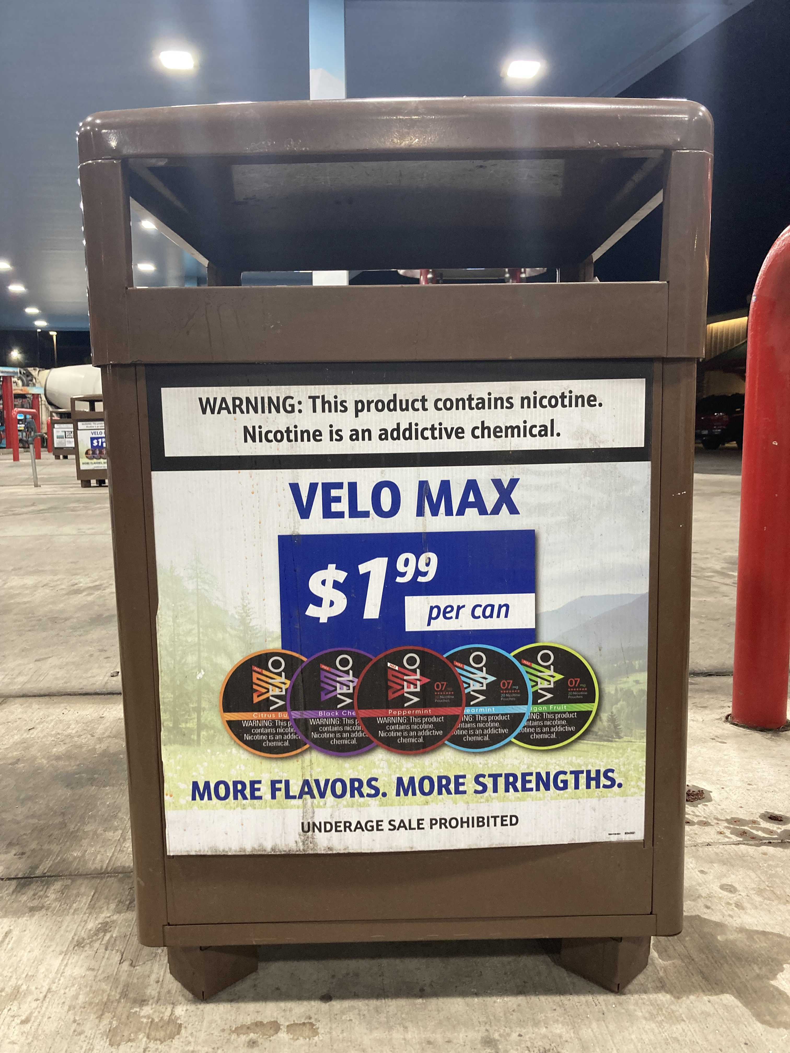 Ad for Velo Max nicotine pouches on a trash can outside at a gas station