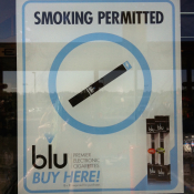 Approx 8" by 11" window cling BLU e-cigarette advertisement saying "Smoking Permitted"; placed at eye level upon entrance to store