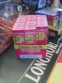 Counter display of cheap cigarillos, next to a map of smokeless tobacco, next to a bowl of candy
