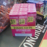 Counter display of cheap cigarillos, next to a map of smokeless tobacco, next to a bowl of candy