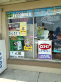 Store window with ads for cigarettes, little cigars, and e-cigarettes.