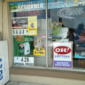 Store window with ads for cigarettes, little cigars, and e-cigarettes.