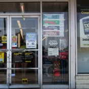 Cigarette ads near candy machines and news clip on the door about store's donation to the reading program of a local elementary school located in a low income neighborhood