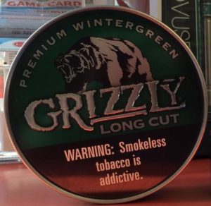 can of Grizzly long-cut premium wintergreen smokeless tobacco with the required warning label "warning:smokeless tobacco is addictive" 