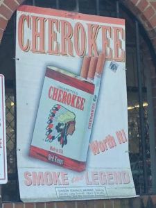 Advertisement for Cherokee brand cigarettes, which feature an image of a person in a traditional Native American headdress and the slogan "smoke the legend." 