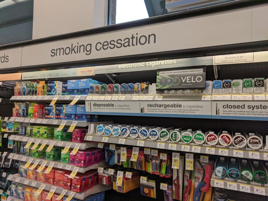 tobacco products under a "smoking cessation" sign in a pharmacy