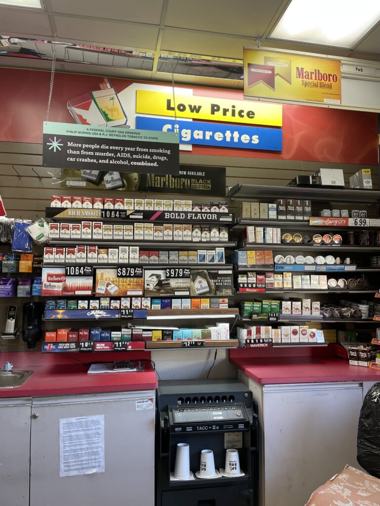 tobacco display behind a counter with a court-ordered corrective statement about the death toll of smoking 